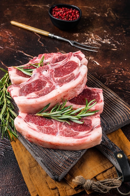 Raw fresh saddle of lamb mutton with herbs and spices on butcher board Dark background Top view