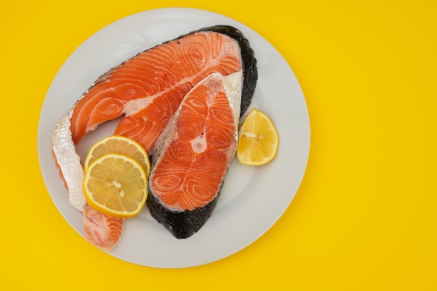 Raw fresh salmon on ceramic plate on yellow