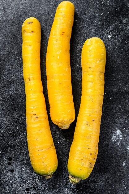 Raw fresh Yellow organic carrots. Black surface. Top view