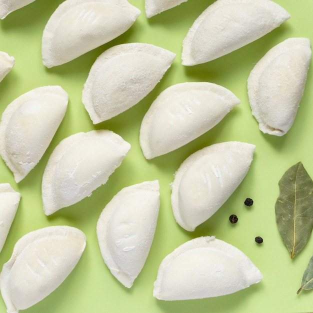 Raw frozen dumplings on green background, top view