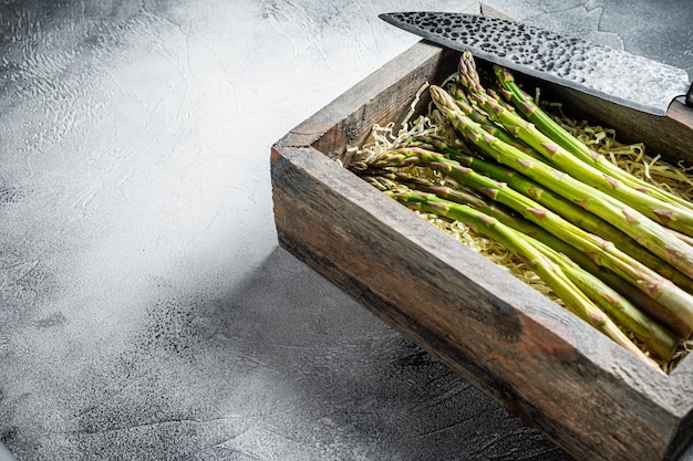 Raw green asparagus in a wooden box White background Top view Copy space