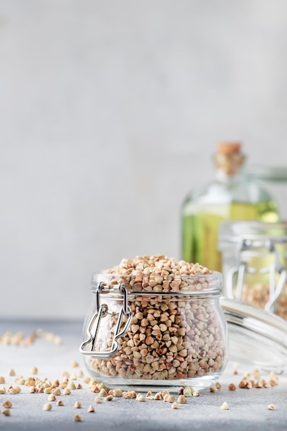 Raw green buckwheat in jar healthy vegetarian food on gray kitchen table copy space selective focus