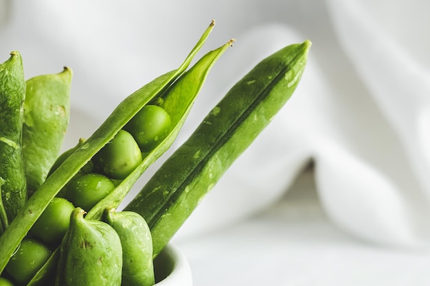 Raw green pea pods on light background