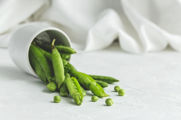 Raw green pea pods on light background