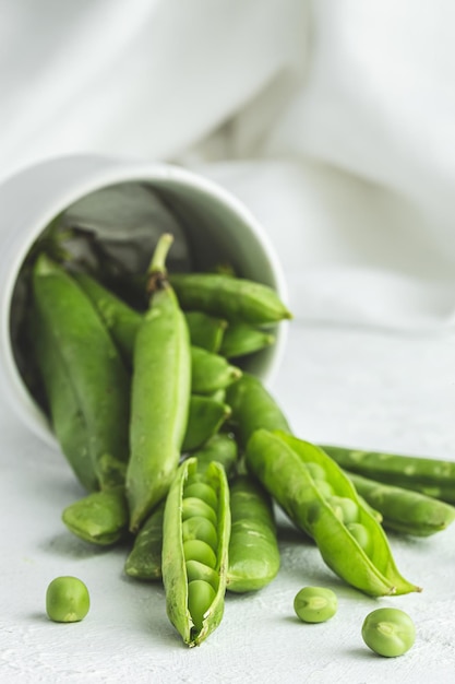 Raw green pea pods on light background