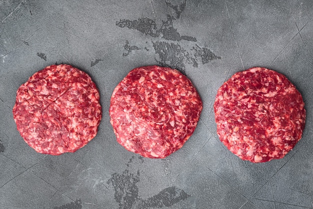 Photo raw ground beef meat burger steak cutlets set, on gray stone