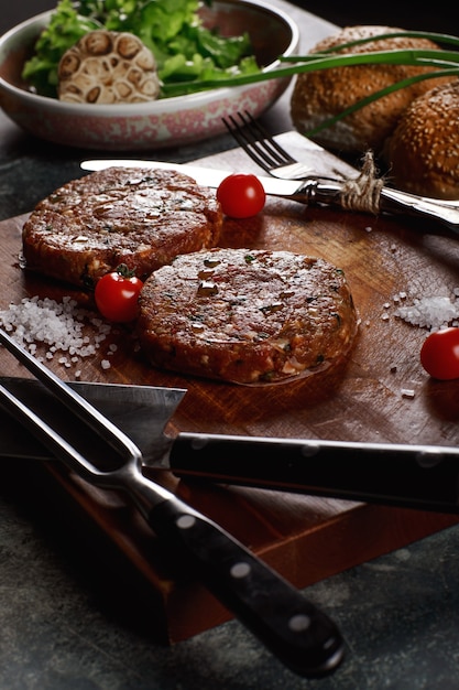 Raw Ground beef meat Burger steak cutlets with ingredients on the board