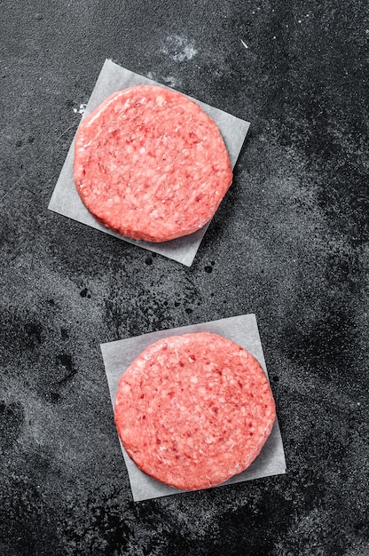 Raw ground meat cutlet, mince beef. Burger patties. Black background. Top view.