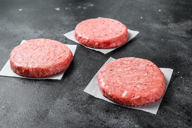 Photo raw ground meat cutlet, mince beef. burger patties. black background. top view.