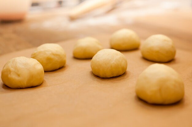 Raw homemade buns on kitchen table in the making