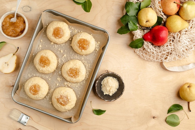 Raw homemade buns made of yeast dough with jam and fresh pears Mini pies Cooking recipe on a wooden background