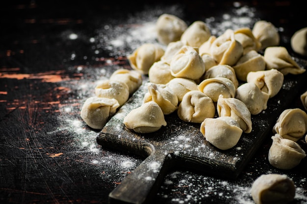 Raw homemade dumplings on a flour cutting board