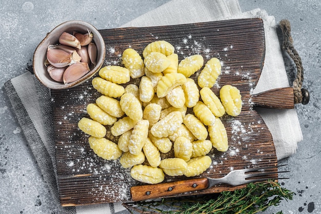 Raw homemade potato gnocchi with fork on wooden cutting board Gray background Top view