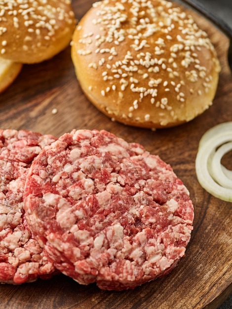 The raw ingredients for the homemade burger Burger patties Raw mince meat cutlet ground beef and pork with bun Grey background