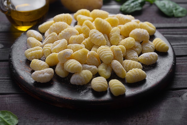 Raw italian gnocchi close up on a dark wooden background. They are dumplings, usually oval, made from wheat flour dough with egg