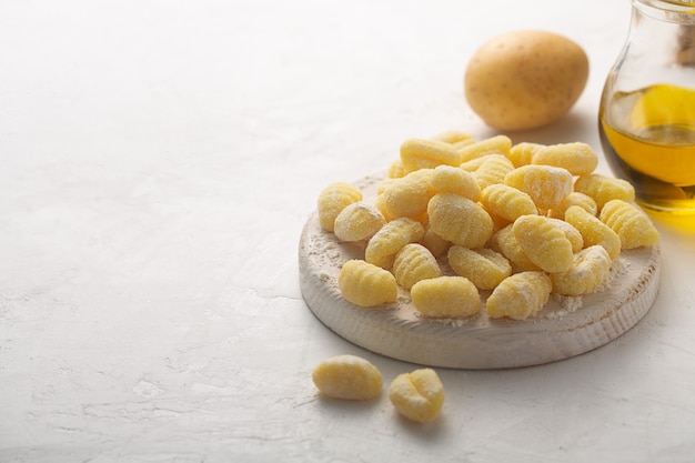 Raw italian gnocchi on a white background with potato and olive oil