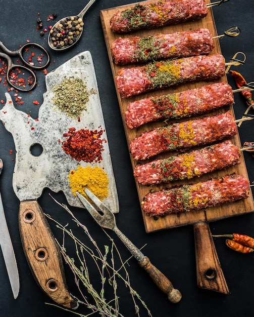 Photo raw kebab with spices and old kitchen ax on a black table