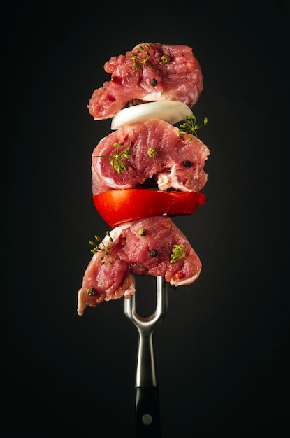 Raw lamb meat with spices and vegetables on a fork Picnic barbecue cooking concept