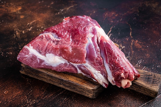 Raw lamb mutton thigh on butcher table. Dark background. Top view.