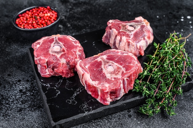 Raw lamb neck meat on a marble board.
Black background. Top view.