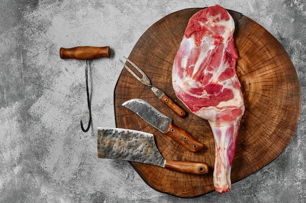 Raw lamb shoulder on butcher's cutting log with tools