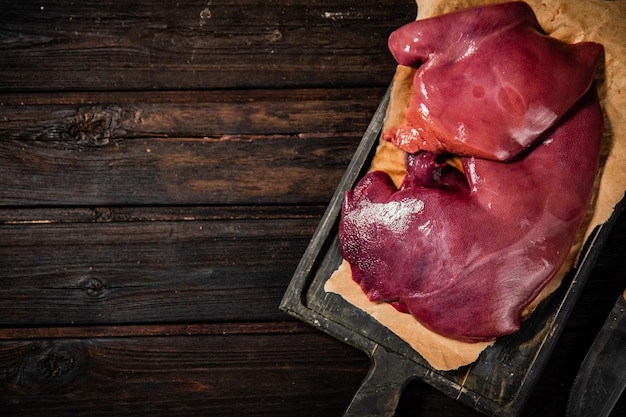 Raw liver on a cutting board on paper