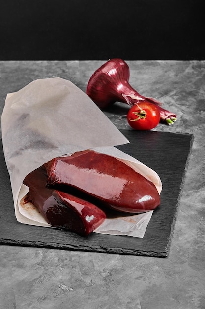 Raw liver on dark wooden background ingredients for cooking liver or pate top view