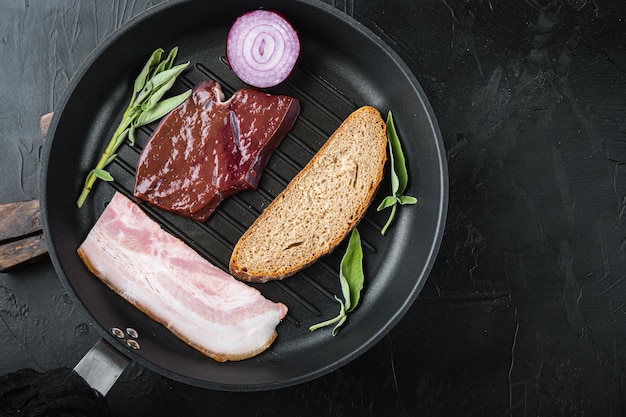 Raw liver sliced with bacon on grill pan on black surfacr flat lay