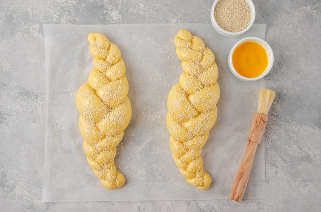 Raw loaf of challah Jewish bread on a light gray background. Top view, copy space.