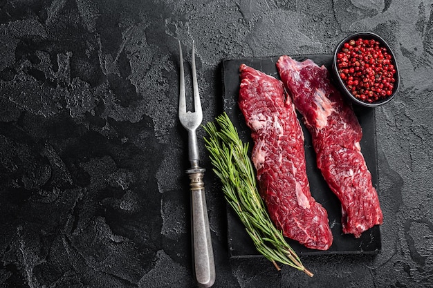 Raw Machete steak or hanging tender cut with herbs Black background Top view Copy space