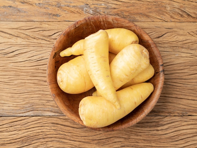 Raw mandioquinha or arracacha in a bowl over wooden table