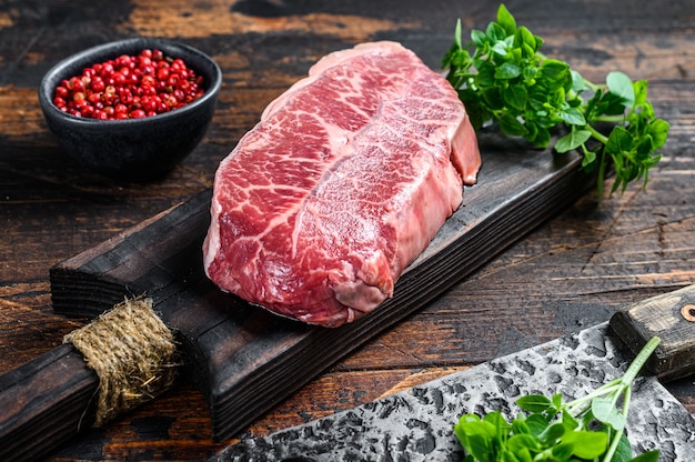 Raw marble beef meat steak. Dark wooden background. Top view.