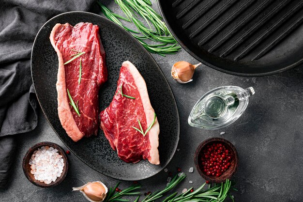 Raw marbled beef steaks and seasonings for their preparation, top view. Raw beef meat on the kitchen table. High quality photo