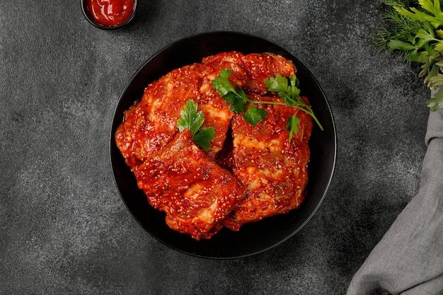 Raw Marinated pork bbq ribs for grill Uncooked ribs in marinade sauce on plate and dark background