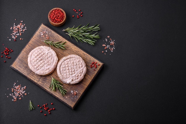 Raw meat balls with spices and herbs or crepinette on a dark concrete background