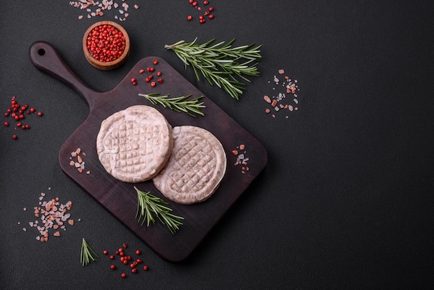 Raw meat balls with spices and herbs or crepinette on a dark concrete background