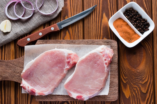 Raw meat on a cutting board with vegetables and spices