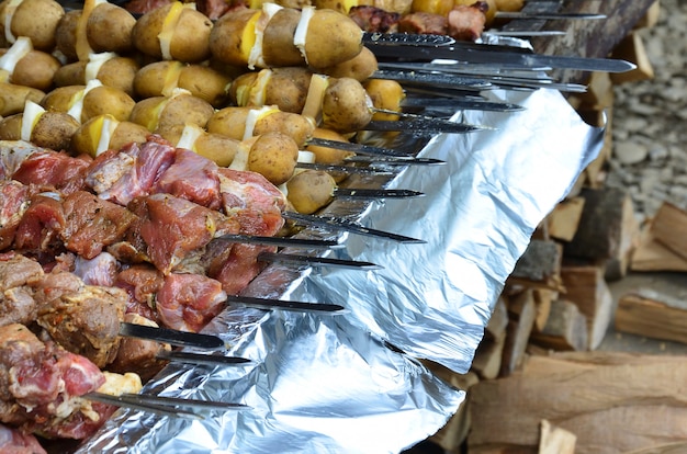 Raw meat and potatoes are planted on metal skewers. The process of cooking shish kebabs.