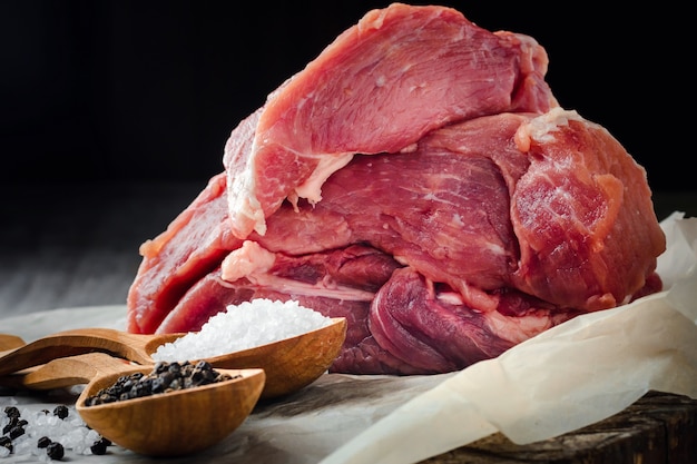 Raw meat, salt and pepper on a black background