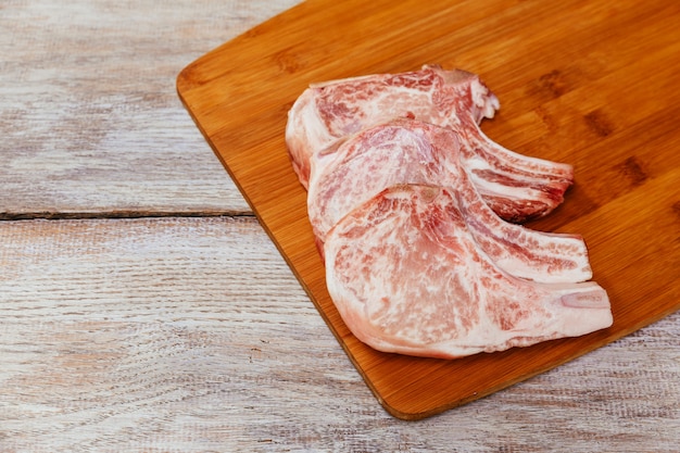 Raw meat steak on dark wooden board.