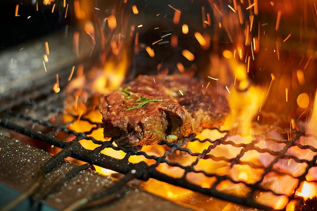 Raw meat steak on grill grate with fire