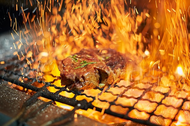 Raw meat steak on grill grate with fire