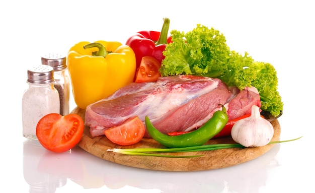 Raw meat and vegetables on a wooden board isolated on white