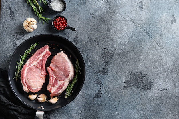 Raw meat with herbs and spices on black slate over grey background