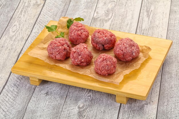 Raw meatball over wooden background