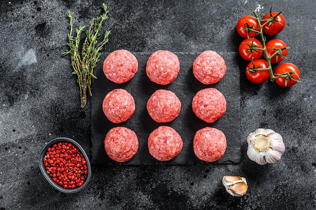 Raw meatballs made from ground beef. Black background. Top view.