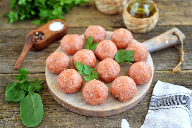 Raw meatballs on a wooden board