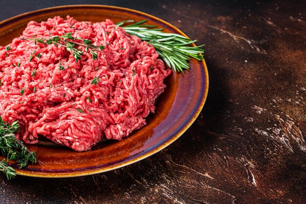 Photo raw mince beef and lamb meat on a rustic plate with herbs. dark background. top view. copy space.