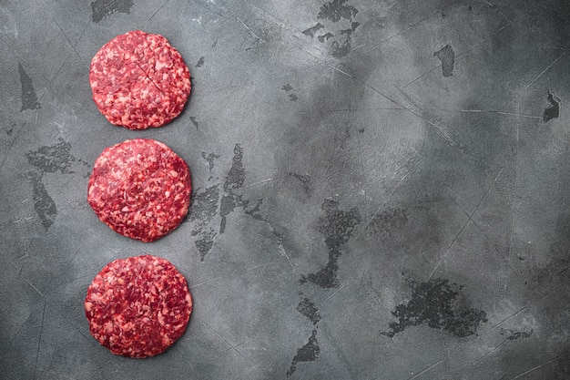 Photo raw minced meat cutlets with herbs and spices set, on gray stone table, top view flat lay