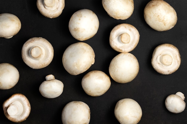 Raw mushrooms champignons on a black background.